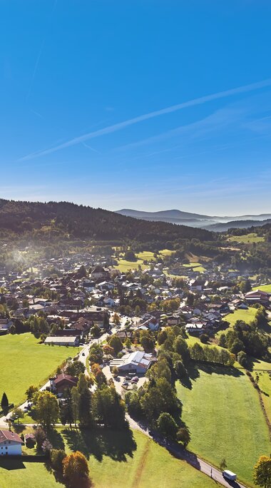 Die grünen Wiesen und Wälder rund um Bodenmais strahlen in der Sonne. Hinter der Ortschaft ragt der Hausberg von Bodenmais, der Silberberg, heraus.  | © Bodenmais Tourismus & Marketing GmbH