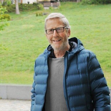 Ein Mann mit grauen Haaren und dunkler Brille steht vor einer Grünfläche und blickt freundlich in die Kamera. Er trägt einen grauen Pulli und eine blaue Jacke.  | © Markt Bodenmais